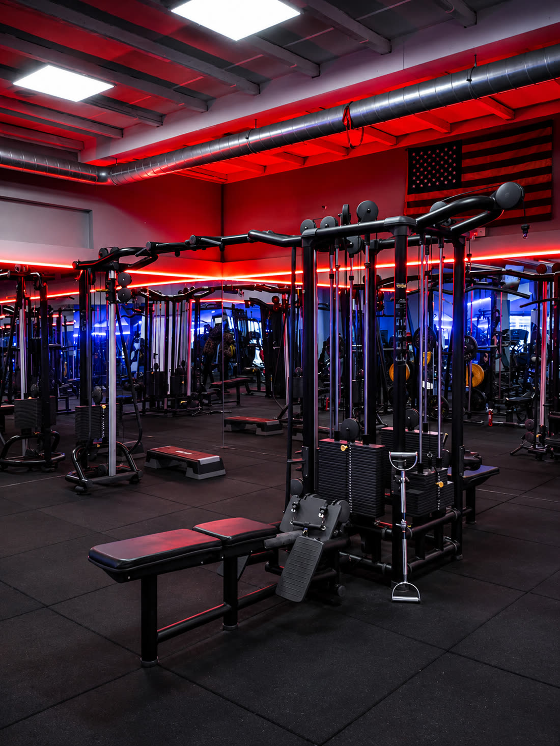 La sala pesi di Nonsolofitness Torvaianica illuminata dai neon rossi, con macchinari isotonici e panche